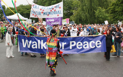 A throng of people march behind the Walk or Peace banner